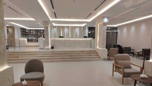 A modern lobby with a reception desk, seating area, and a staircase leading to an upper level. - HAYAT ROSE AL Madinah AL Munawwarah  (Madinah)