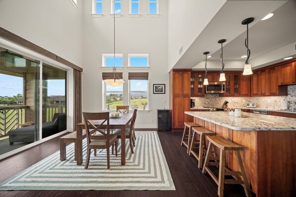 A modern kitchen with a large island, wooden cabinets, and a view to the outdoors. - New Listing 3 Bedroom on the Golf Course in sunny Poipu (Koloa)