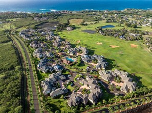 A residential area with houses, a golf course, and a body of water in the background. - New Listing 3 Bedroom on the Golf Course in sunny Poipu (Koloa)