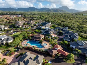 A residential area with a swimming pool, houses, and a mountainous backdrop. - New Listing 3 Bedroom on the Golf Course in sunny Poipu (Koloa)