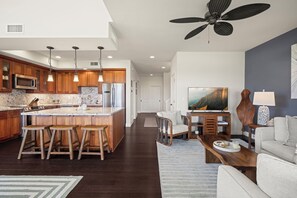 A modern kitchen with wooden cabinets, a central island with stools, stainless steel appliances, and pendant lighting. - New Listing 3 Bedroom on the Golf Course in sunny Poipu (Koloa)