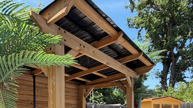 Eine Holz-Pergola mit Bank, einem kleinen Schuppen und einem Blumentopf.