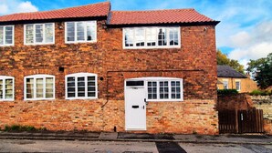 A two-story brick house with a red-tiled roof, white-framed windows, and a white door. - Spacious & Luxury 2BR Flat in Calverton (Calverton)