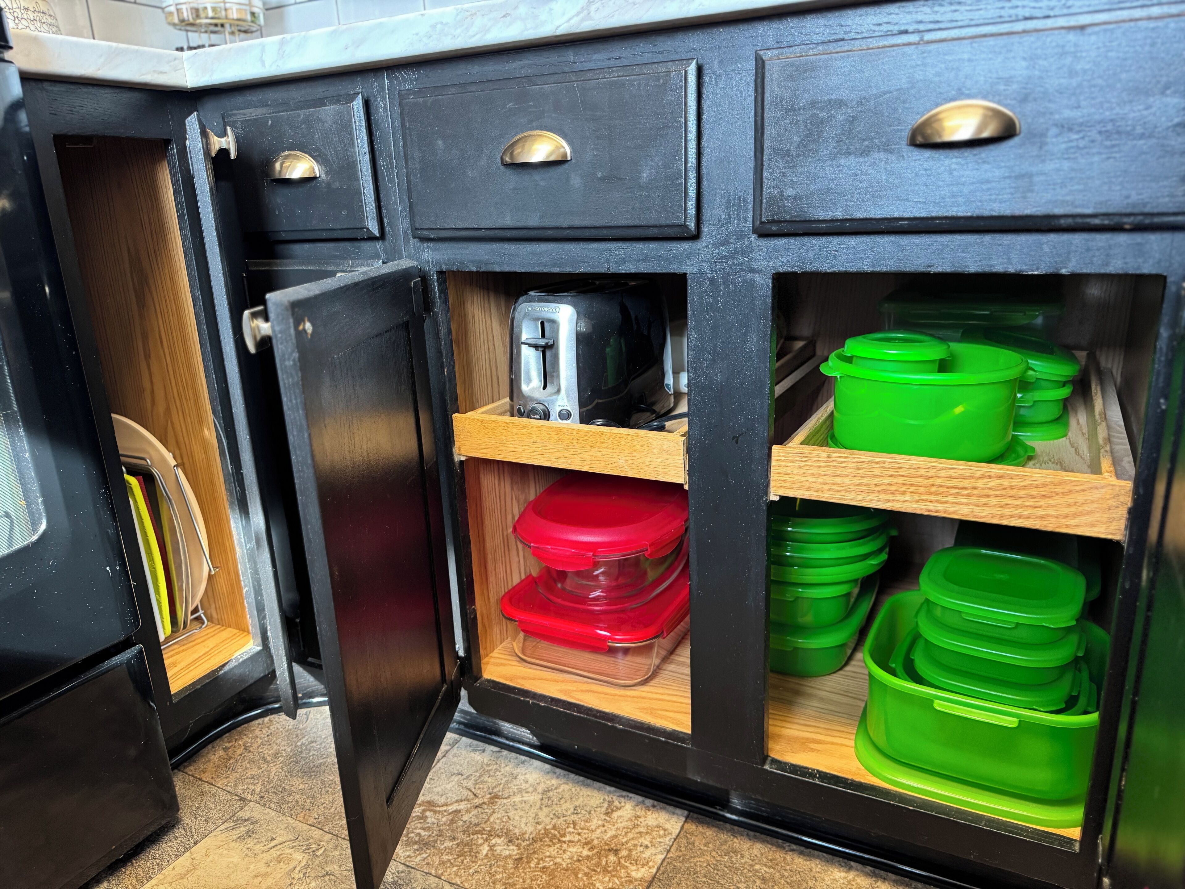 A kitchen with black cabinets, a toaster, and green and red containers.