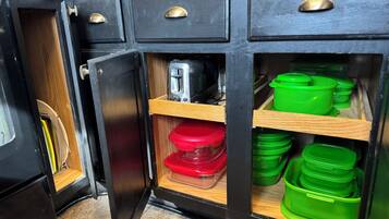 A kitchen with black cabinets, a toaster, and green and red containers.