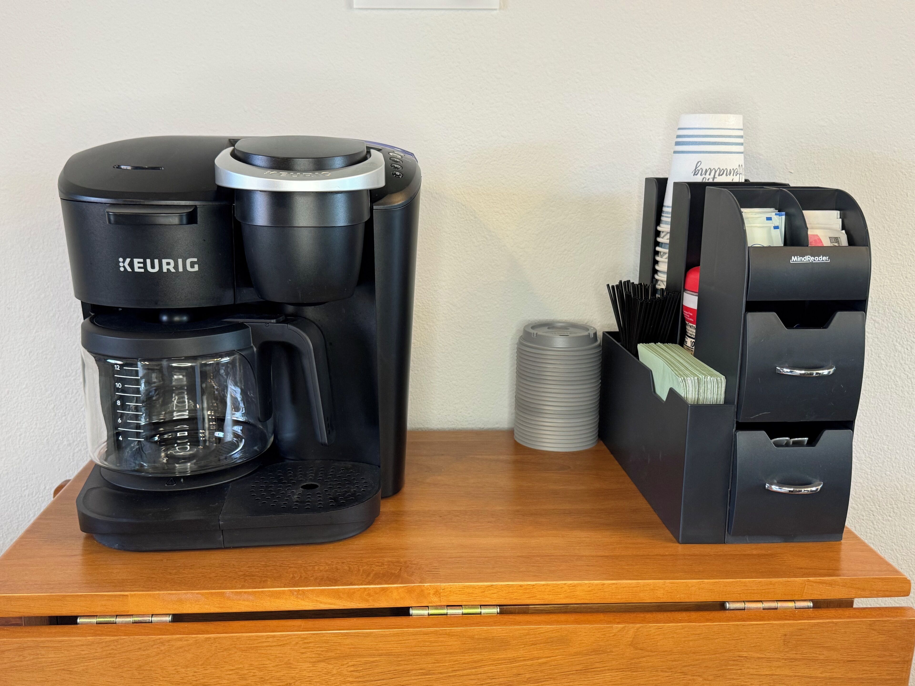 En Keurig-kaffemaskin och en MindReader-kortläsare står på ett träbord.