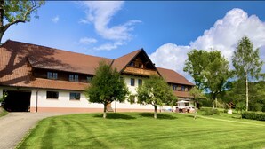 A two-story building with a sloped roof, a paved driveway, and a well-maintained lawn. - Apartment “Schellenberg” with Mountain View, Private Terrace, and Wi-Fi (Herrischried)