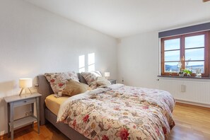 Un dormitorio con cama, mesitas de noche, ventana con vistas y un radiador.
