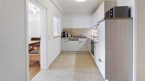 A modern kitchen with white cabinetry, a wooden countertop, and a built-in oven. - Apartment “Schellenberg” with Mountain View, Private Terrace, and Wi-Fi (Herrischried)