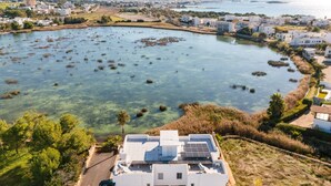 A coastal residential area with clear water, white buildings, and a house with solar panels. - Holiday Home 'Rosso' with Private Terrace, Wi-Fi and Air Conditioning (Scala di Furno)