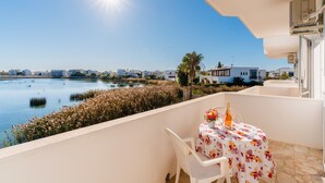 A balcony with a table set for two, overlooking a body of water and a cityscape. - Holiday Home 'Rosso' with Private Terrace, Wi-Fi and Air Conditioning (Scala di Furno)