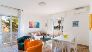A modern living room with a sofa, chairs, a dining table, and artwork on the walls. - Holiday Home 'Rosso' with Private Terrace, Wi-Fi and Air Conditioning (Scala di Furno)