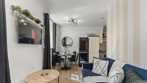A compact living space with a dining area, a sofa, a small round table, and a kitchenette. - Lovely Duplex for Long Stays - Parking (Dewsbury)