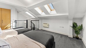 A bedroom with two beds, skylights, a staircase, a radiator, and a potted plant. - Lovely Duplex for Long Stays - Parking (Dewsbury)