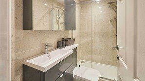 A modern bathroom with a white sink, dark cabinets, a large mirror, and a glass-enclosed shower area. - Host & Stay | Ross's View, First Floor, Apartment 3 (Whitby)