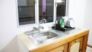 A kitchen with a stainless steel sink, a dish rack, and a dish soap bottle. - Sunset view suite personal Patio wiew panoramic mountain view and sunset (Trou D'eau Douce)