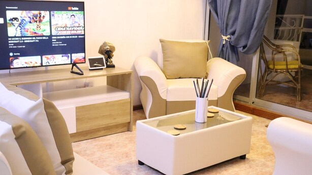 A modern living room with a flat-screen TV, comfortable seating, and a glass coffee table. - Sunset view suite personal Patio wiew panoramic mountain view and sunset (Trou D'eau Douce)
