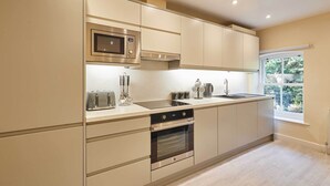 A modern kitchen with stainless steel appliances, a built-in oven, and a window providing a view of the outdoors. - Host & Stay | Ross's View, Second Floor, Apartment 4 (Whitby)