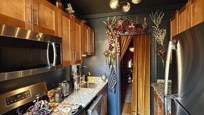 A modern kitchen with stainless steel appliances, wooden cabinets, and a marble countertop. - Designer Corner Unit Suite, Cozy 1-bedroom apt, Laundry, AC, (New York)