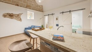 Una cocina moderna con encimera de mármol, pared de piedra y una lámpara colgante.
