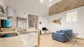 Una cocina moderna con horno empotrado, un área de comedor con sofá azul y una pared de piedra.