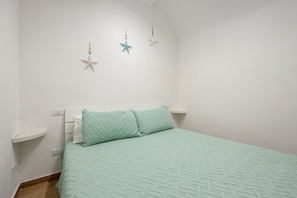 A bedroom with a bed, two pillows, a nightstand, and three wall decorations.