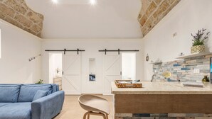 Una cocina moderna con una isla de madera, un sofá azul y una silla blanca.