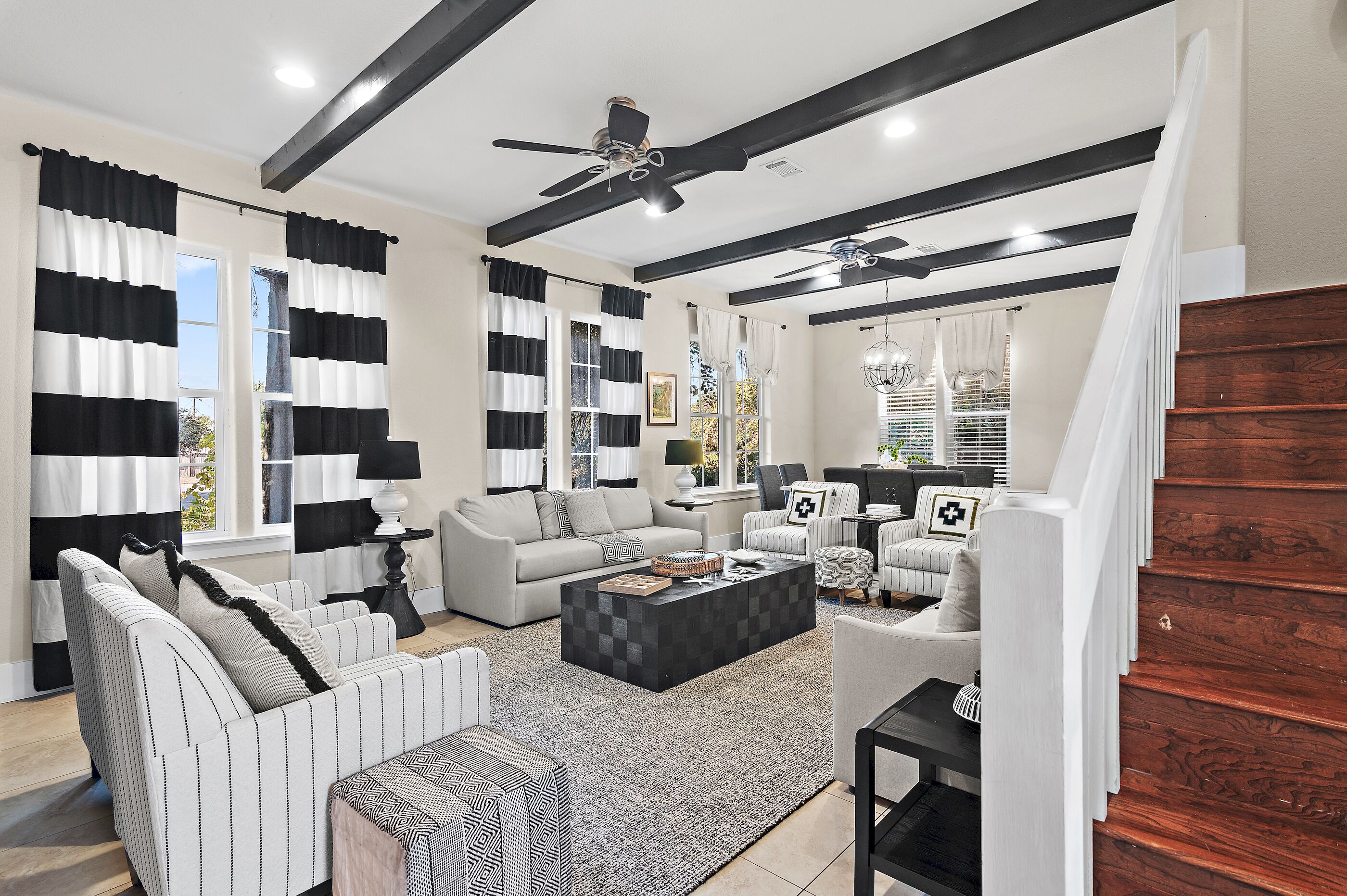 A modern living room with a sofa, armchairs, a coffee table, and a staircase.