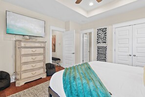 Ein Schlafzimmer mit einem Bett, einem Schminktisch, einem Fernseher und zwei Türen.