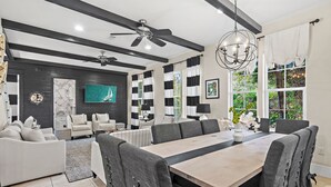 A modern living room with a dining area, featuring a large table, grey upholstered chairs, a ceiling fan, and a chandelier. - ⭐Pet Friendly | 4 Bikes | Walk to Beach | Villa Soleil Dunes⭐ (Miramar Beach)