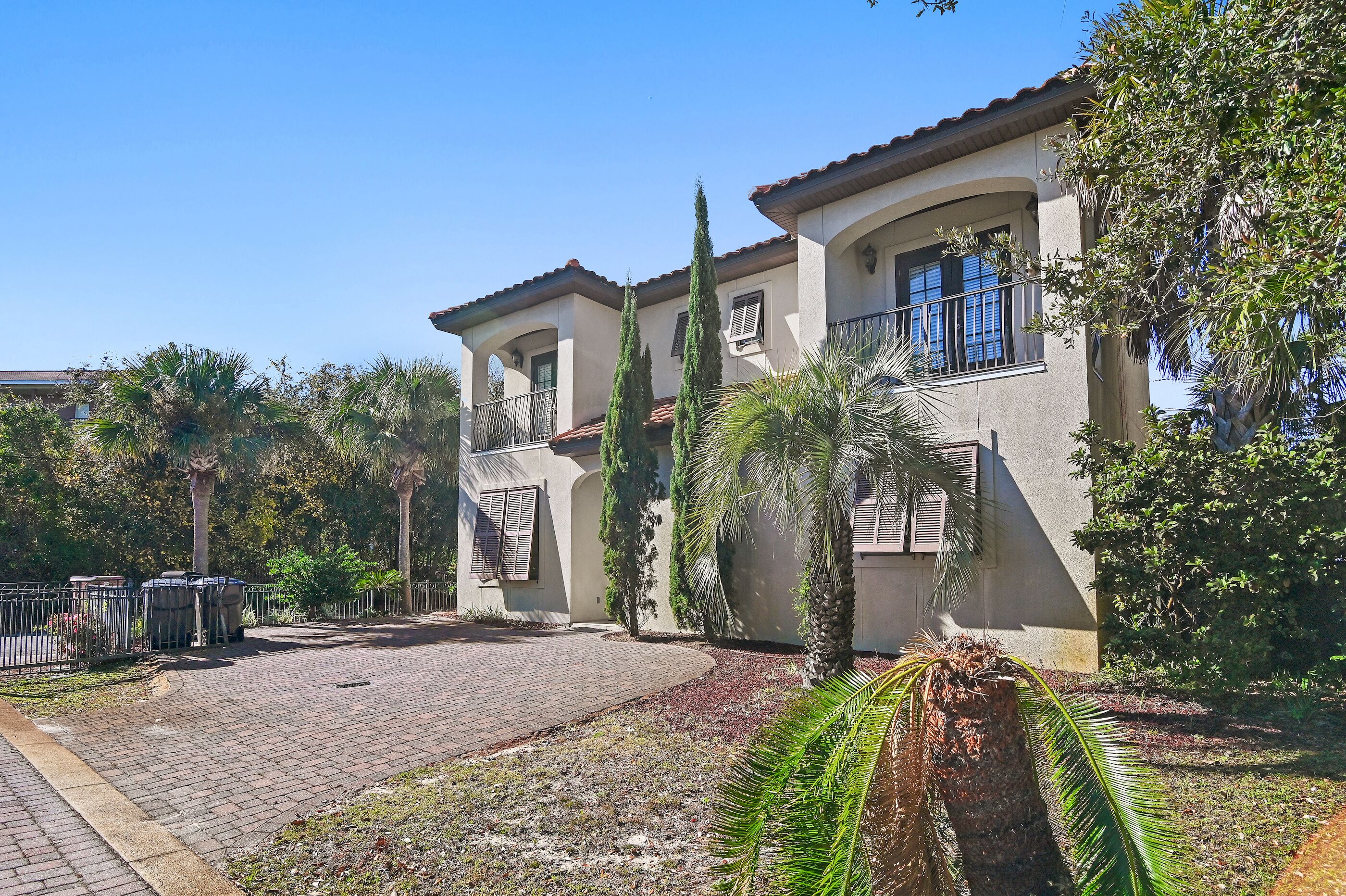 A two-story house with a tiled roof, a balcony, and a paved driveway.