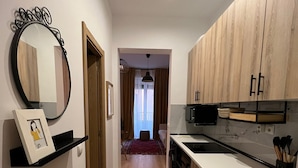 A modern kitchen with wooden cabinets, a black microwave, and a white countertop. - w* | Bright 1BR with Balcony in Madrid Centro (Madrid)