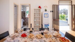 A dining table set with plates, glasses, and food, with a refrigerator and shelves in the background. - Holiday Home 'Villa Destra' with Private Terrace, Wi-Fi and Air Conditioning (Porto Cesareo)