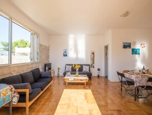 A living room with a sofa, coffee table, and dining area. - Holiday Home 'Villa Destra' with Private Terrace, Wi-Fi and Air Conditioning (Porto Cesareo)