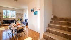 A spacious living area with a dining table, sofa, and a staircase. - Holiday Home 'Villa Destra' with Private Terrace, Wi-Fi and Air Conditioning (Porto Cesareo)