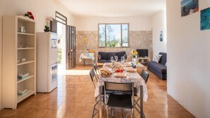 A dining area with a table set for four, a sofa, a TV, and a stone wall. - Holiday Home 'Villa Destra' with Private Terrace, Wi-Fi and Air Conditioning (Porto Cesareo)