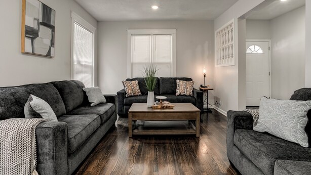 A living room with two dark grey sofas, a wooden coffee table, and a potted plant. - Stylish & Cozy Apartment with Modern Updates (Kansas City)