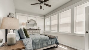 A bedroom with a bed, dresser, lamp, and large windows. - Stylish & Cozy Apartment with Modern Updates (Kansas City)