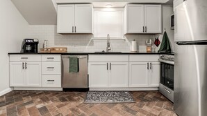 A modern kitchen with white cabinets, a stainless steel refrigerator, and a tiled backsplash. - Stylish & Cozy Apartment with Modern Updates (Kansas City)