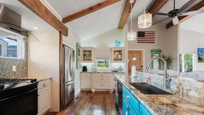 A kitchen with wooden beams, a stainless steel refrigerator, and a granite countertop.