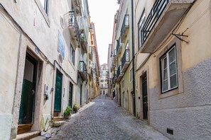A narrow cobblestone street flanked by buildings with balconies and windows. - Camões Lounge Apartment w/Courtyard (Lisboa)