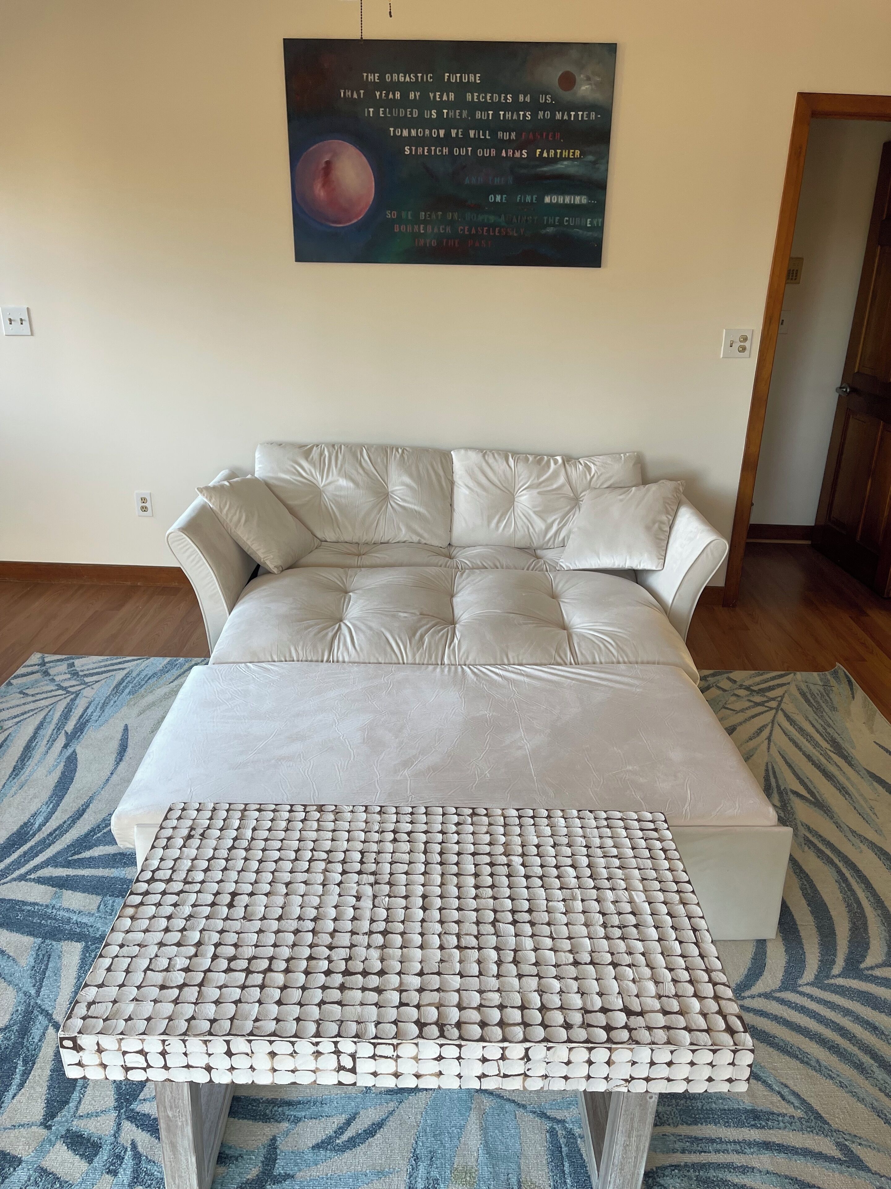 A bedroom with a bed, a decorative wall hanging, and a unique wooden coffee table.