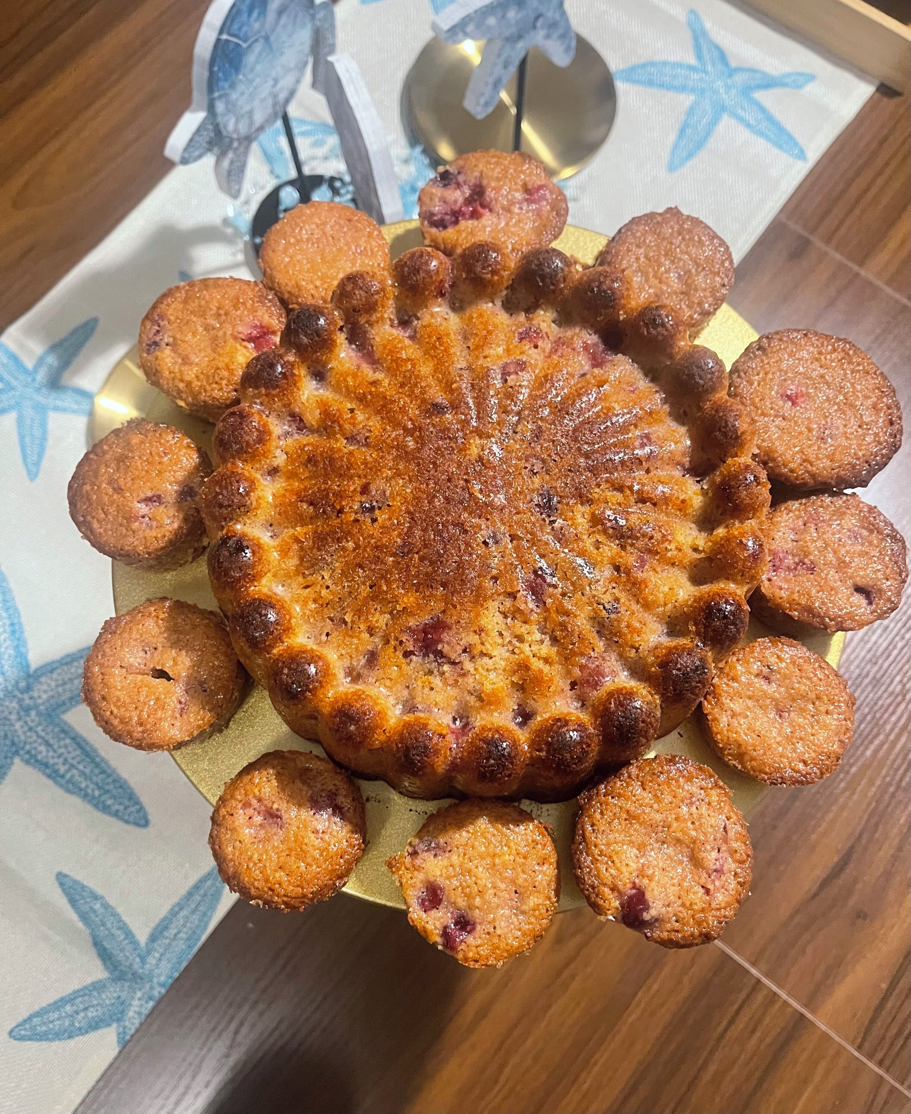 A round dessert with a golden-brown crust, surrounded by smaller round pieces, on a plate with a star pattern.