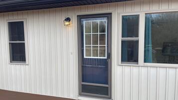 Een laag gebouw met een donkerblauwe voordeur, witte gevelbekleding en een klein raam aan de linkerkant.