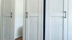 A set of white wooden wardrobe doors with black handles.