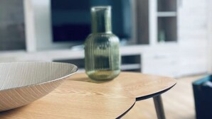 A modern interior with a wooden table, a glass bowl, and a green vase.