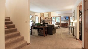 A spacious living area with a staircase, a fireplace, a television, and a dining table. - I1 Gore Creek Meadows -Gorgeous Mountain Home, Private Hot Tub! (Vail)