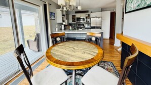 A modern kitchen with white cabinets, stainless steel appliances, and a dining area with a round table and chairs. - Stunning Pet Friendly House with Pond View, Sauna and Jetted Tub in the Home (Killington)