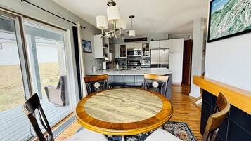 A modern kitchen with white cabinets, stainless steel appliances, and a dining area with a round table and chairs.