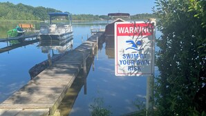 Un quai avec des bateaux, un panneau d’avertissement et un lac paisible.